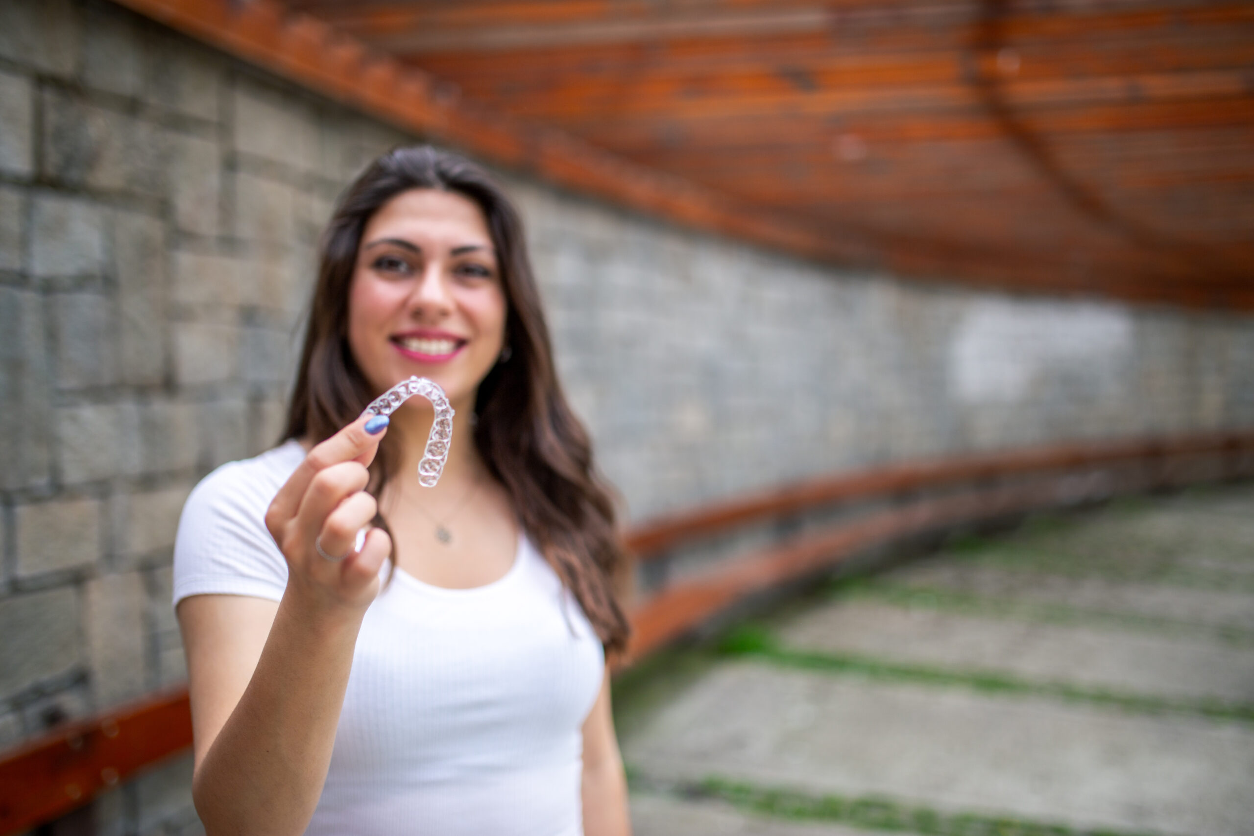 Woman holding a clear Invisalign aligner tray and smiling in Nashua