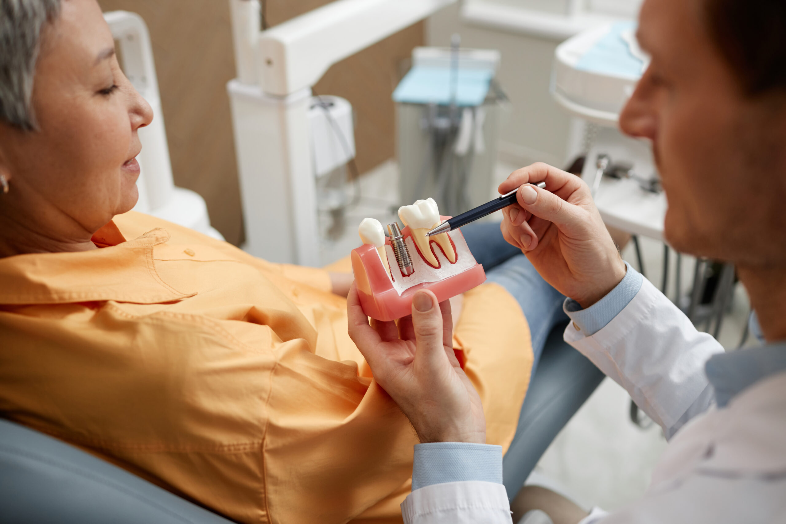 Nashua dentist explaining dental implant model to patient during consultation