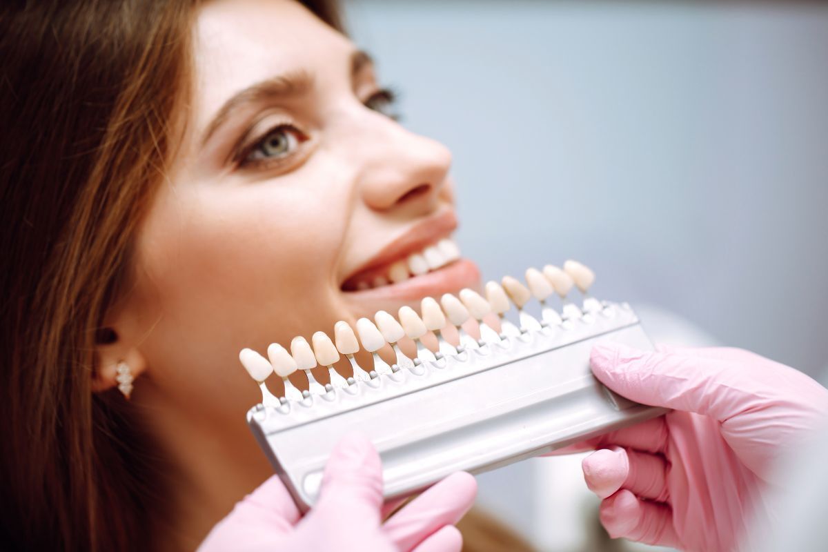 Patient examining dental veneer shade guide to compare tooth color options for cosmetic dental treatment.